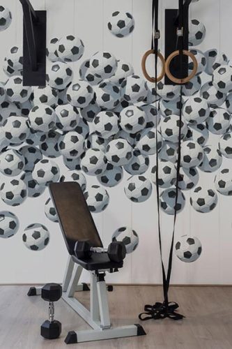 Seamless black and white flying watercolor football balls wall mural in minimalistic gym interior. Monochrome Fancy Walls wallpaper peel and stick or non-pasted