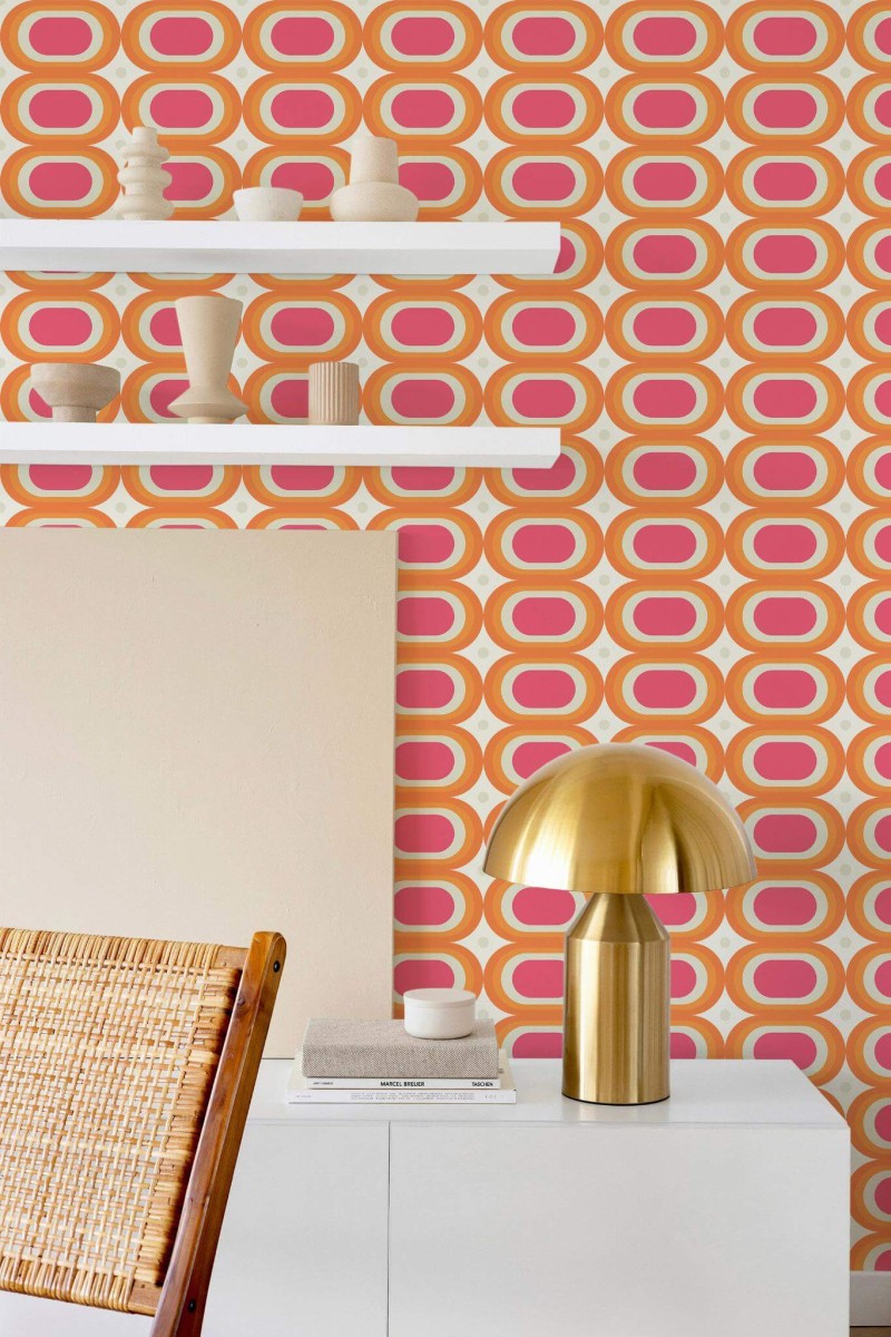 Retro peel and stick wallpaper with bold pink, orange, and yellow oval pattern styled in a modern room with brass lamp and shelf decor.