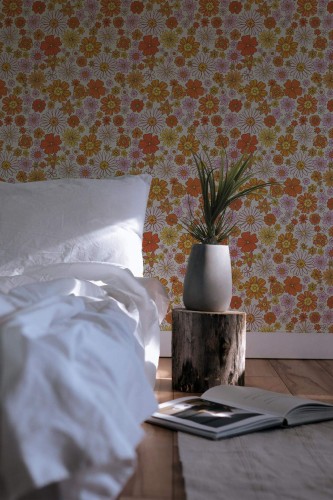 70s floral peel and stick wallpaper in retro orange, yellow, and pink tones styled in a cozy boho bedroom with wood and white accents