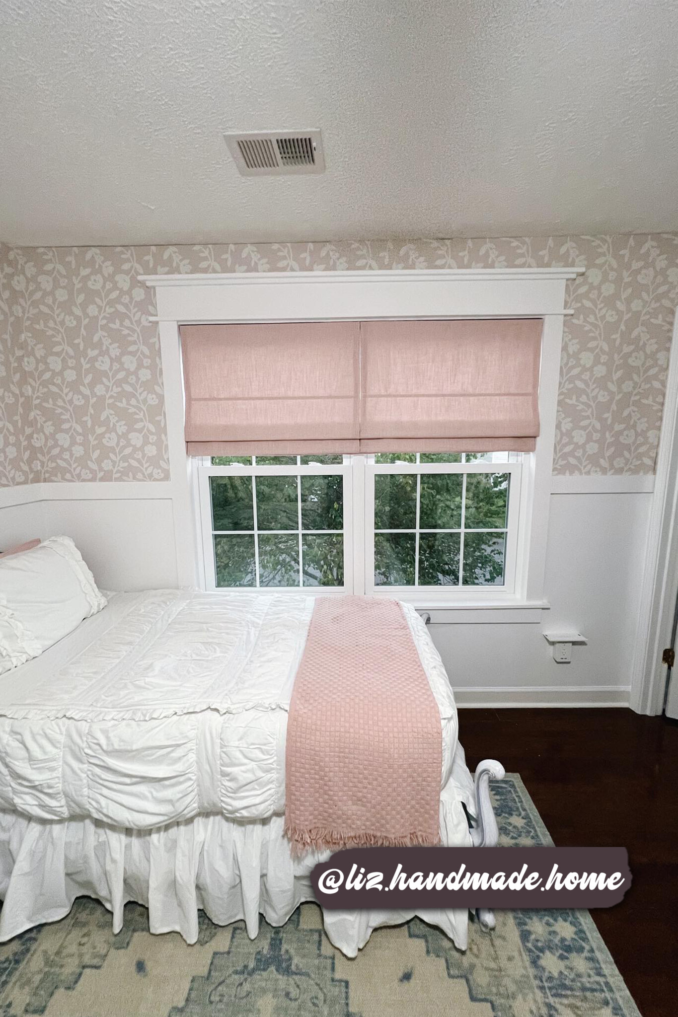 Soft pink floral wallpaper with delicate white botanical patterns, adding a cozy and feminine touch to a bedroom with white wainscoting and vintage-inspired decor