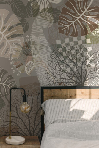 Peel and stick wall murals featuring abstract tropical leaf shapes with intricate paisley details in earthy grays, browns, and greens, ideal for bedrooms and cozy interiors. The Fancy Walls peel and stick or non-pasted wallpaper.
