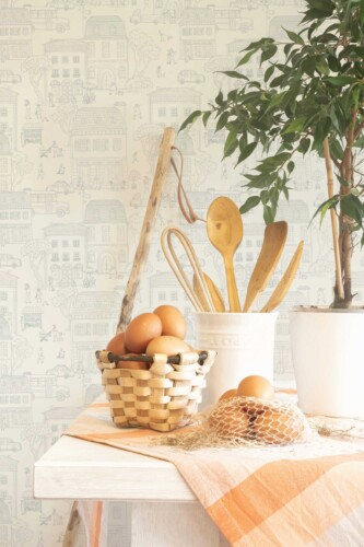 Kitchen counter scene with eggs, utensils, and natural textures placed in front of the beige city wallpaper design. The wallpaper’s calm, illustrated townscape creates a cozy and nostalgic setting perfect for cafés, cottage-style kitchens, or bakery-inspired interiors. Fancy Walls’ soft neutral pattern brings understated charm to walls while maintaining a fresh, airy look.