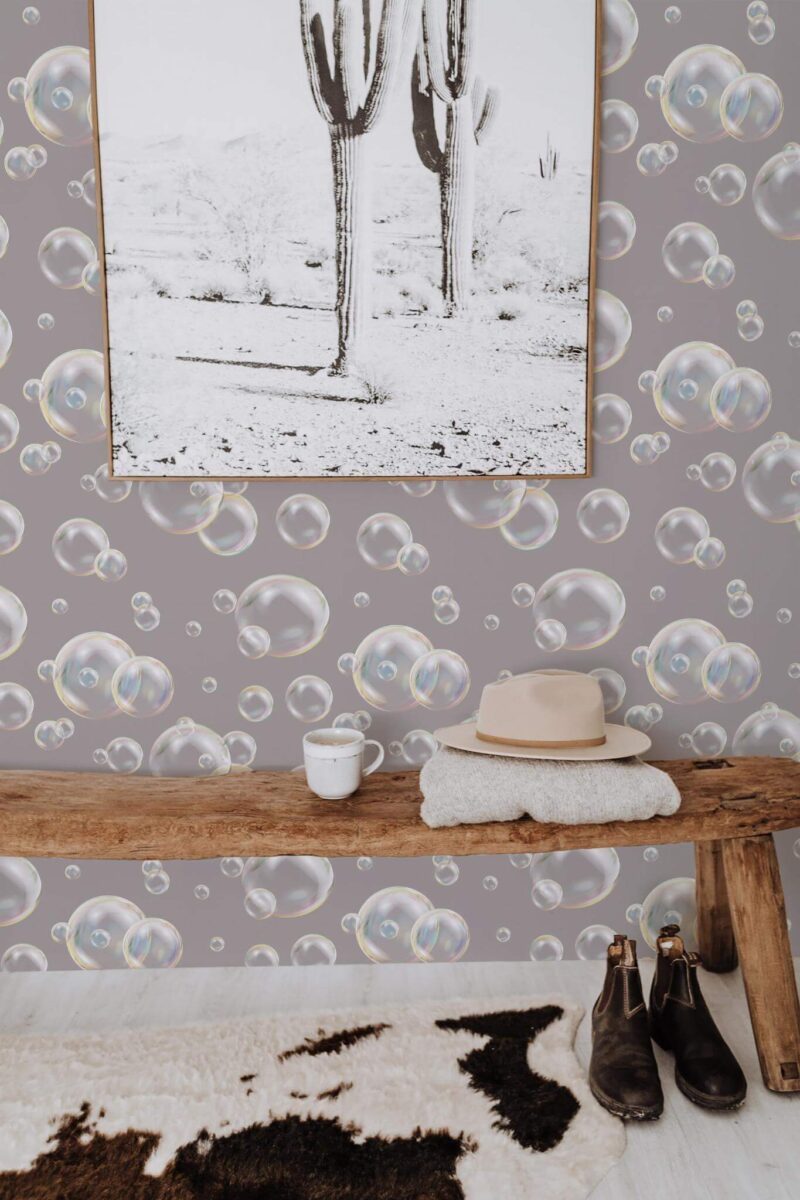 Realistic floating bubble wallpaper with a subtle gray background, displayed in a cozy entryway featuring a wooden bench, southwestern cactus print, boots, and warm neutral accents. The design adds whimsical charm while maintaining a modern, sophisticated feel.