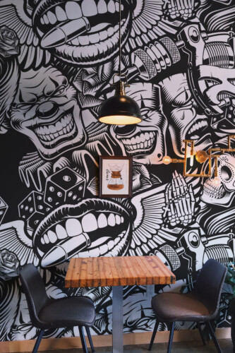 Wall mural peel and stick style in monochrome street art pattern with clown faces, tattoo elements, and skulls for bold barber shop walls. The Fancy Walls peel and stick or non-pasted wallpaper.