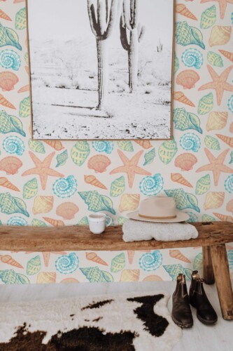 Coastal seashell peel and stick wallpaper with colorful shells and starfish in beach-style entryway with rustic bench and boots