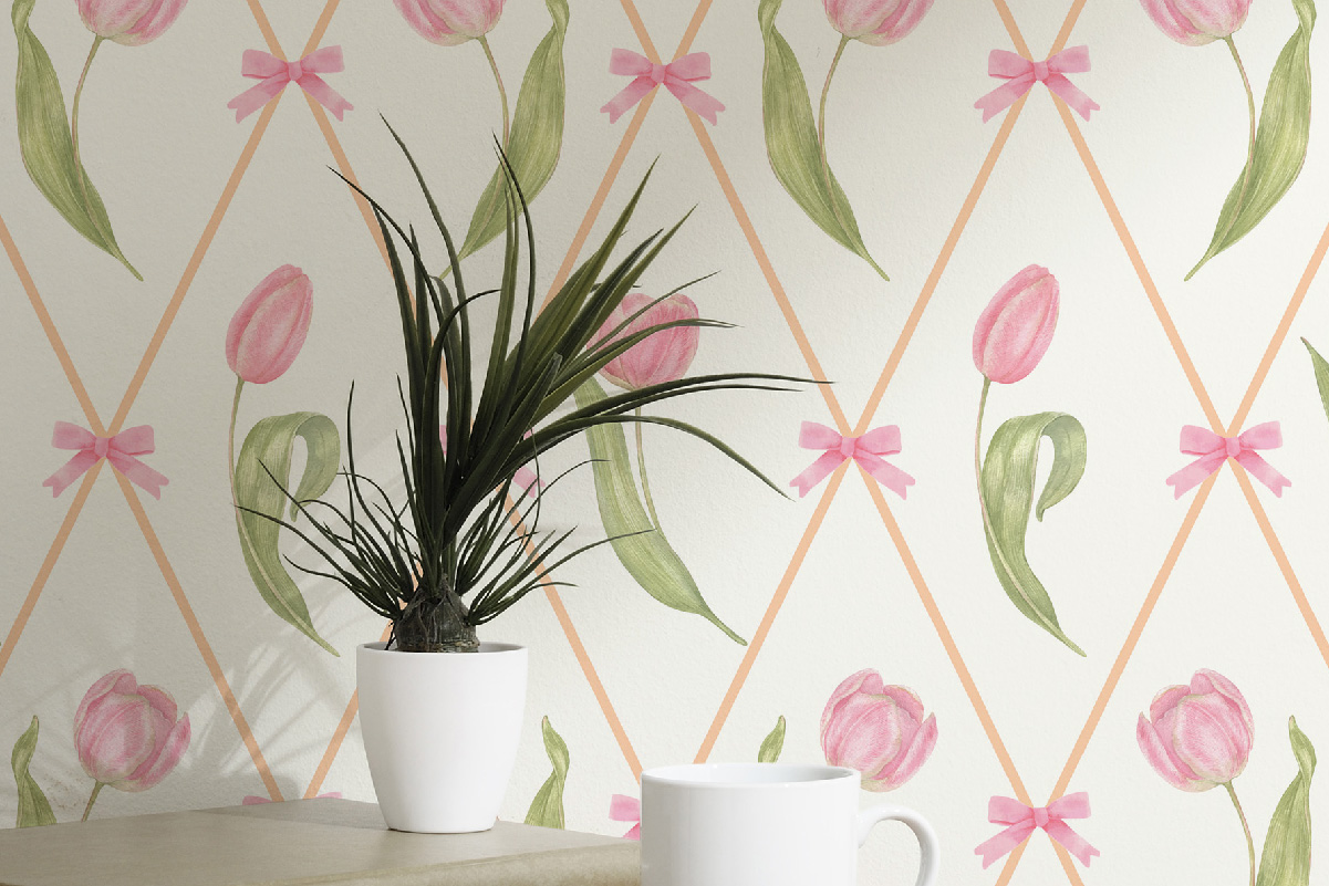 Light pink tulip wallpaper with peach lattice and bows behind a potted plant and white mug – whimsical floral wallpaper, removable and fabric-based.