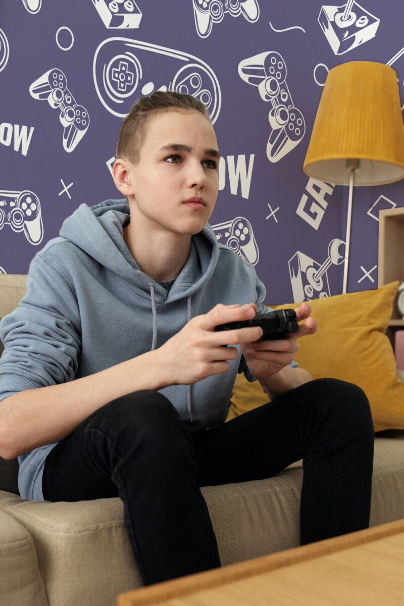 Bold Purple Gamepad Pattern wall mural with purple background, white gamepads, joysticks, and playful gaming icons, ideal for game rooms, teen bedrooms, or fun accent walls.