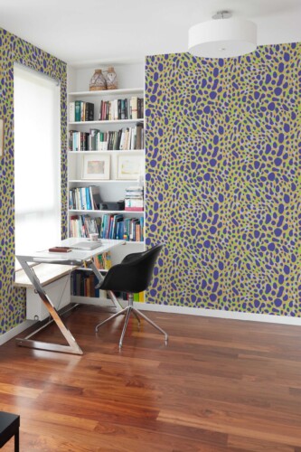 A bright and contemporary home office featuring Fancy Walls “Electric Wildcat” wallpaper, styled with a bold cheetah-inspired pattern in electric green and deep purple on a light tan background. The abstract spots create a dynamic, energetic effect, making the accent wall a vibrant focal point in the room. Paired with sleek furnishings, a modern white desk, black chair, built-in bookshelf, and polished wood flooring, the space balances productivity with personality. Available in peel and stick or non-pasted formats, this PVC-free wallpaper is printed with GreenGuard Gold certified inks for vivid color and clean indoor air.