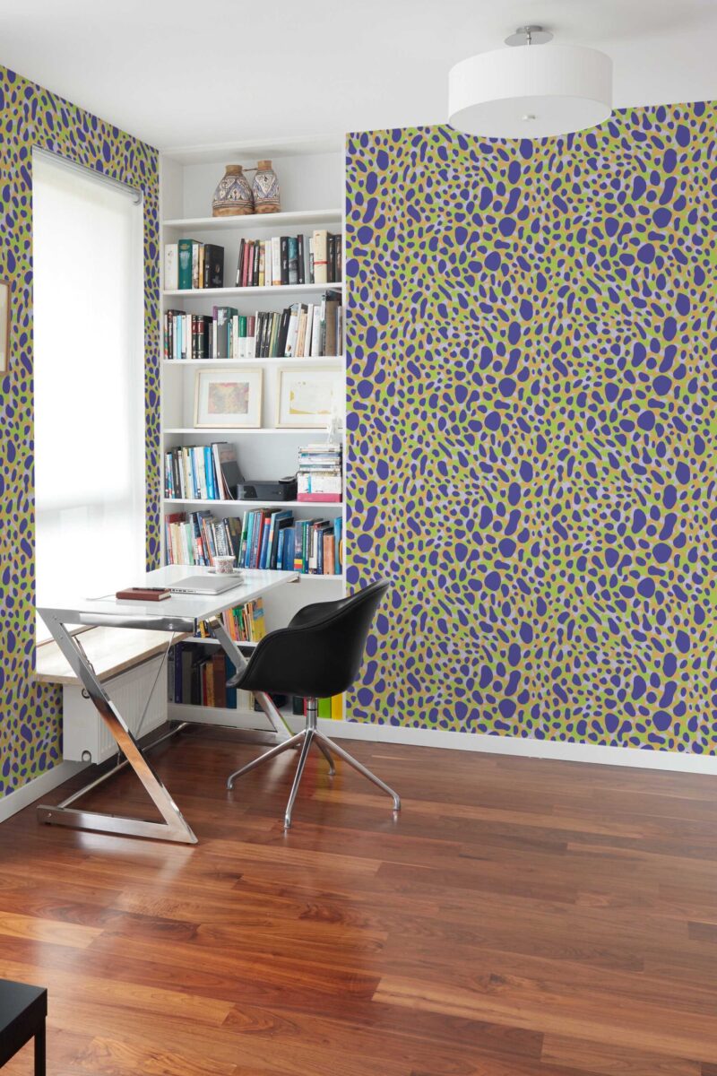 A bright and contemporary home office featuring Fancy Walls “Electric Wildcat” wallpaper, styled with a bold cheetah-inspired pattern in electric green and deep purple on a light tan background. The abstract spots create a dynamic, energetic effect, making the accent wall a vibrant focal point in the room. Paired with sleek furnishings, a modern white desk, black chair, built-in bookshelf, and polished wood flooring, the space balances productivity with personality. Available in peel and stick or non-pasted formats, this PVC-free wallpaper is printed with GreenGuard certified inks for vivid color and clean indoor air.