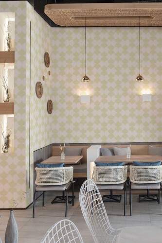 Cozy café booth seating area styled with Cozy Coffee Shop Classic wallpaper. The repeating geometric pattern adds a subtle vintage aesthetic, creating a welcoming atmosphere perfect for casual dining and conversation.