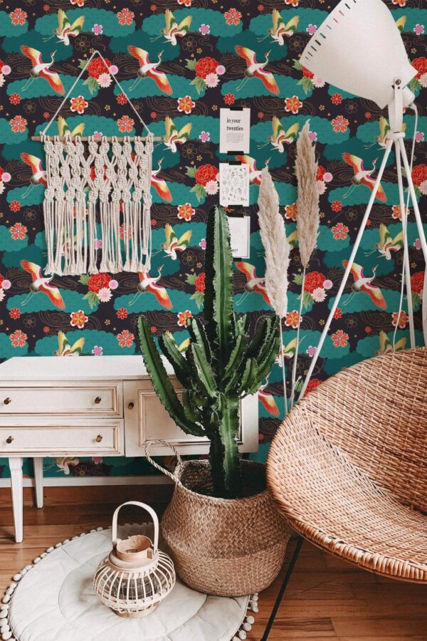 Maximalist Bird Wallpaper with vivid teal background, showcasing colorful birds, blooming flowers, and lively foliage, styled in a bohemian space with a macramé wall hanging, tall cactus, rattan chair, and a warm wood floor. The bold pattern infuses the room with an energetic, whimsical atmosphere.