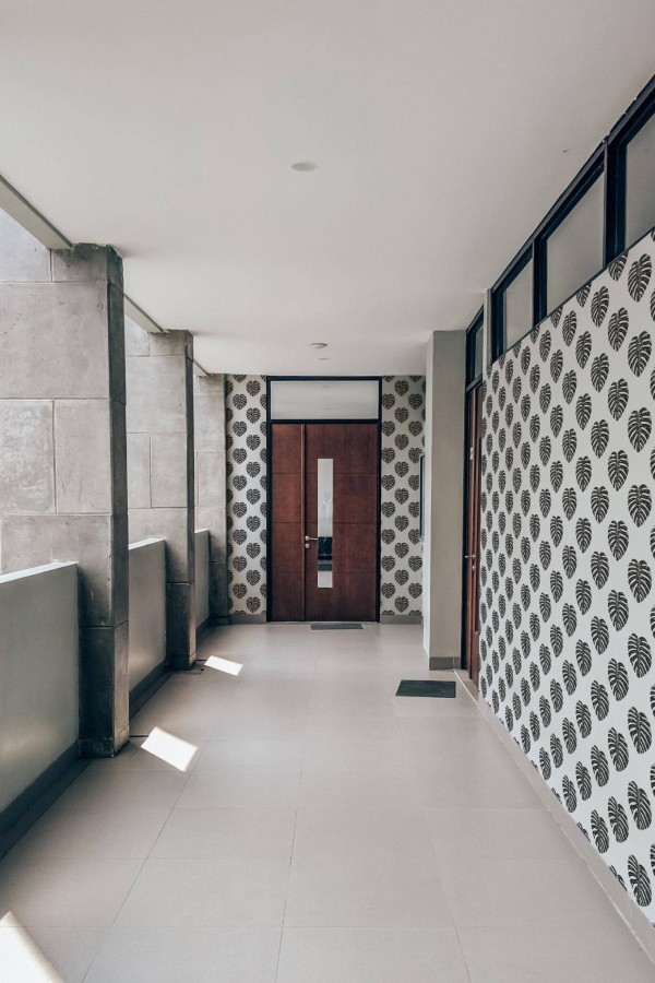 Industrial style hallway with a balcony decorated with Minimalist Monstera leaf peel and stick wallpaper