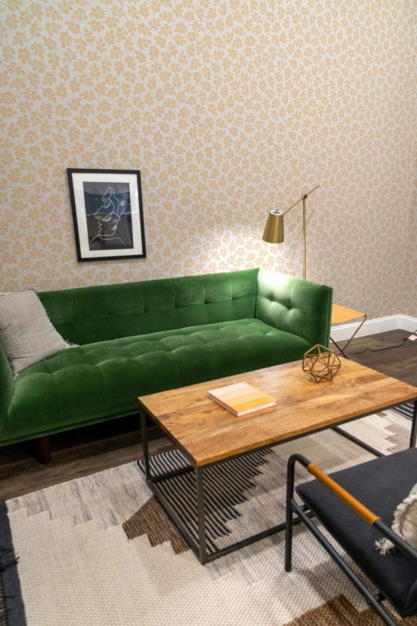 Mid-century modern living room decorated with Orange and white leaf peel and stick wallpaper and forest green sofa
