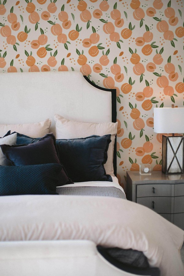 Peach Aesthetic wallpaper with hand-drawn peaches and green leaves on white, styled in a cozy bedroom with neutral bedding and velvet pillows.