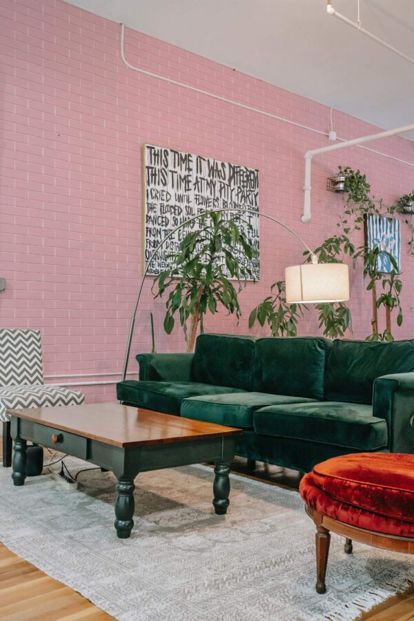 Bold eclectic style living room decorated with Pink bricks peel and stick wallpaper and emerald green sofa