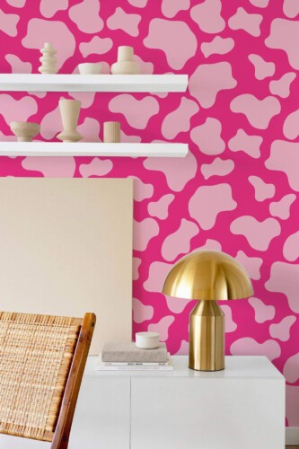 Pink cow pattern peel and stick wallpaper in abstract living room with modern gold lamp and floating white shelves