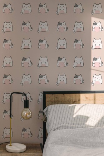 Pink wallpaper featuring a repeating pattern of cute, stylized cat faces in soft tones. Displayed in a cozy bedroom with a wooden bed frame, minimalist bedding, and an industrial-style lamp, creating a playful yet calming atmosphere.