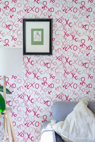 Pink XO brushstroke preppy peel and stick wallpaper in eclectic living room with gray sofa and framed art