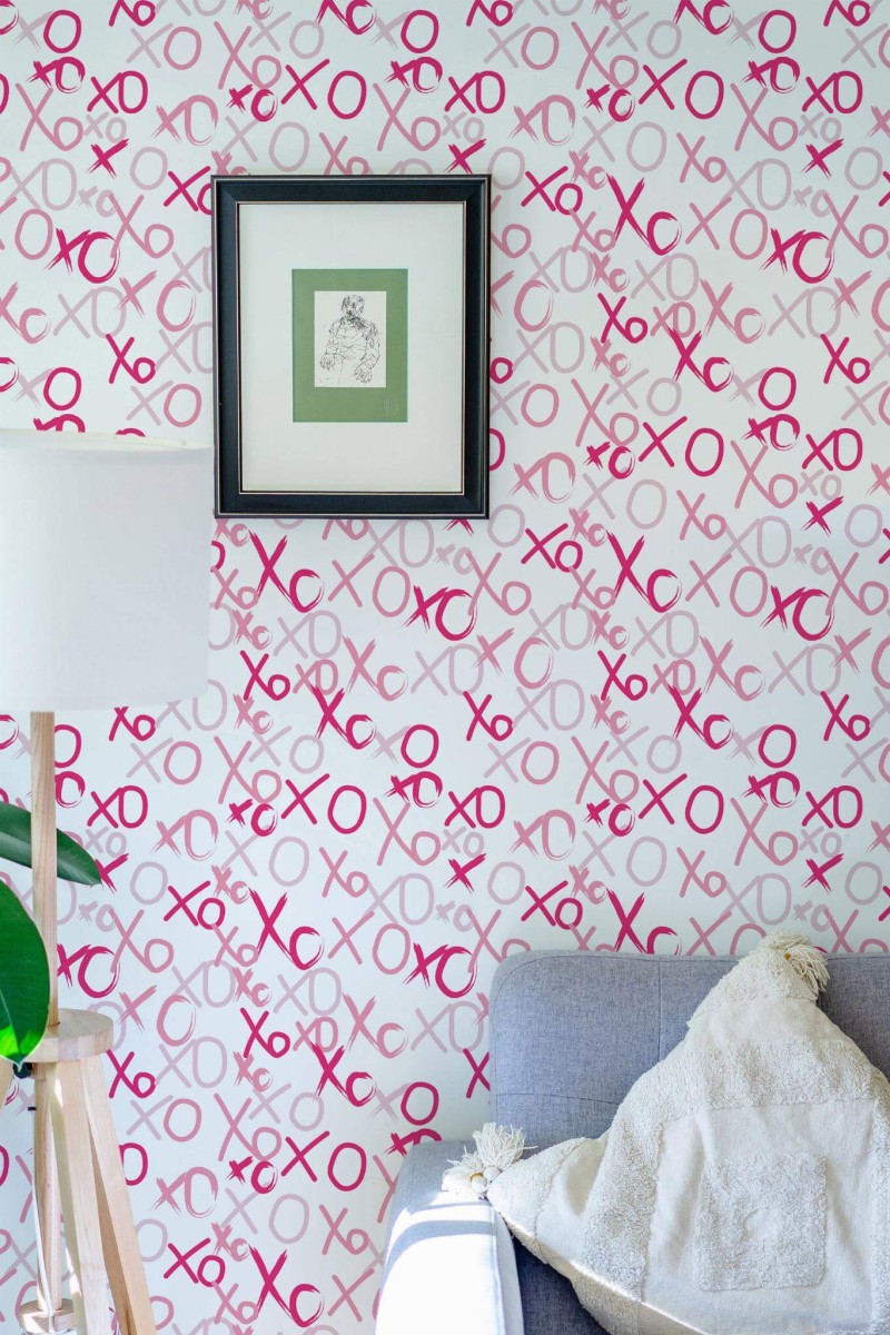 Pink XO brushstroke preppy peel and stick wallpaper in eclectic living room with gray sofa and framed art
