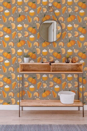 Autumn Pumpkin Spice Wallpaper with a repeating pattern of orange pumpkins, pumpkin pie slices, spiced lattes, and seeds on a warm taupe background. The cozy, seasonal farmhouse-style wallpaper adds festive charm to a hallway styled with a rustic wooden console table, round mirror, and small potted plants, creating a welcoming fall-inspired interior.