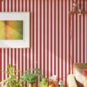 Red and white striped peel and stick wallpaper in a cozy living room with houseplants and modern wooden decor
