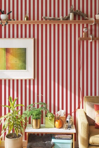 Red and white striped peel and stick wallpaper in a cozy living room with houseplants and modern wooden decor