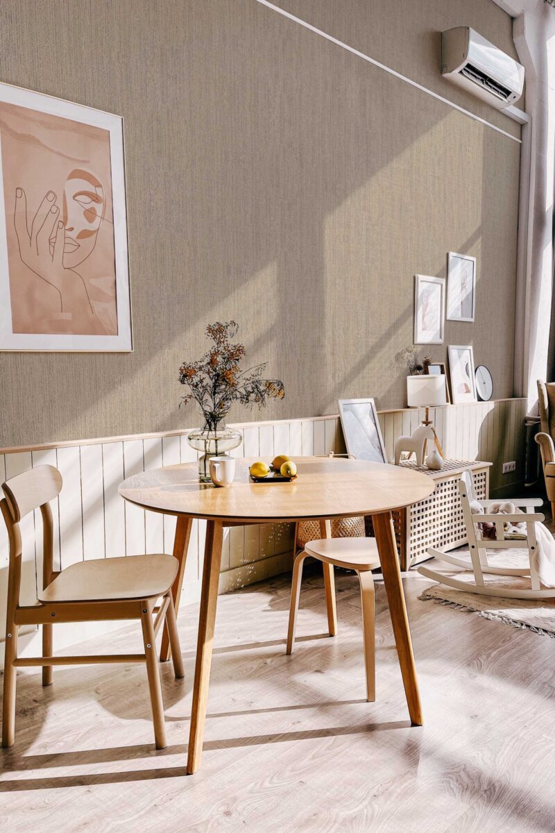 Scandinavian-style dining nook with light wood furniture and minimalist decor, enhanced by the soft woven texture of the Fog Retro Talbott Grasscloth wallpaper in taupe-beige. The design brings a sense of warmth and quiet sophistication. Fancy Walls removable peel and stick or non-pasted wallpaper.