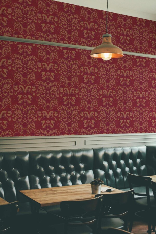 Burgundy Elegance Wallpaper with an ornate ochre damask pattern on a rich red background, styled in a sophisticated bar interior featuring tufted black leather seating, wooden tables, and a warm industrial pendant lamp. The luxurious design adds timeless charm and a refined atmosphere to the space.