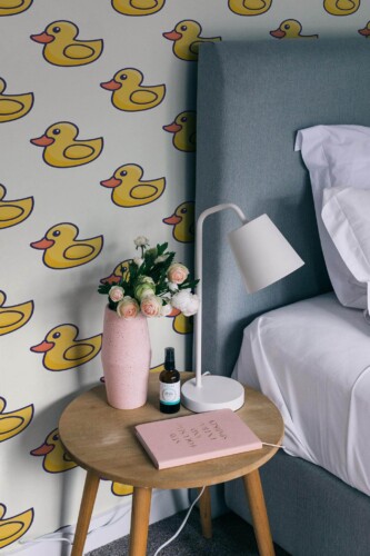 Rubber duck peel and stick wallpaper in a rustic bedroom with wooden accents and a cozy upholstered bed.