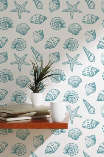 Dark cyan seashell and starfish peel and stick wallpaper in Scandinavian coastal style behind shelf with books and coffee mug