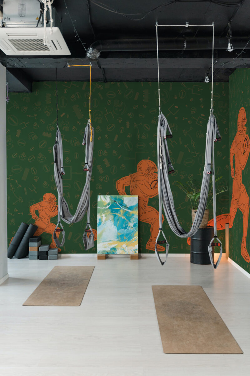 American Football Action Wall Mural with bold orange players on a green field background, perfect for gym interiors and sporty accent walls.