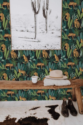 A richly detailed wallpaper design featuring golden-yellow cheetahs lounging and stalking through a dense, stylized jungle of teal, emerald, and sage green leaves. The vivid dark backdrop contrasts beautifully with the layered foliage and animals, creating a dramatic, exotic ambiance. This design adds bold energy to entryways, lounges, or creative studios and pairs well with earthy textures and natural wood tones. The Fancy Walls peel and stick or non-pasted wallpaper is ideal for renters and homeowners alike, bringing wild charm to any space.