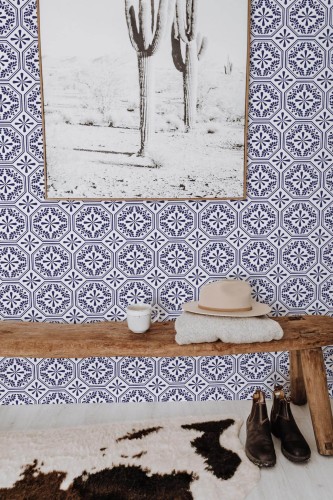 Spanish Tile wallpaper in blue and white octagonal pattern, styled in an entryway with rustic bench, cactus art, and cowhide rug.