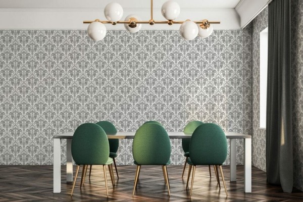 Classic damask gray wallpaper in a vintage Art Deco motif serves as the backdrop to a cozy mid-century living room. The symmetrical scroll design enhances the white wall, contrasting with warm leather furniture and Scandinavian-inspired textiles. A large indoor fig tree in a sleek planter and minimalist gold lighting elevate the natural charm of the space, combining elegance with earthy accents for a stylish statement wall.