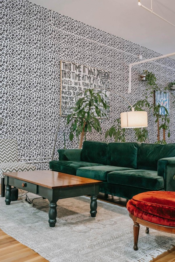 Bold eclectic style living room decorated with Leopard print peel and stick wallpaper and emerald green sofa
