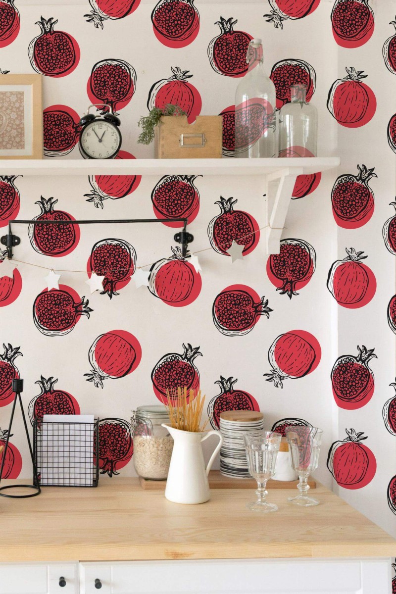 Vibrant pomegranate wallpaper featuring red and black fruit outlines on a crisp white background, displayed in a bright kitchen with a wooden countertop, open shelves, and minimal decor.