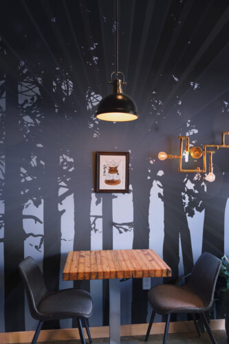 Fancy Walls Dark Woods wall mural peel and stick capturing rays of light shining between tall black trees in a moody atmosphere