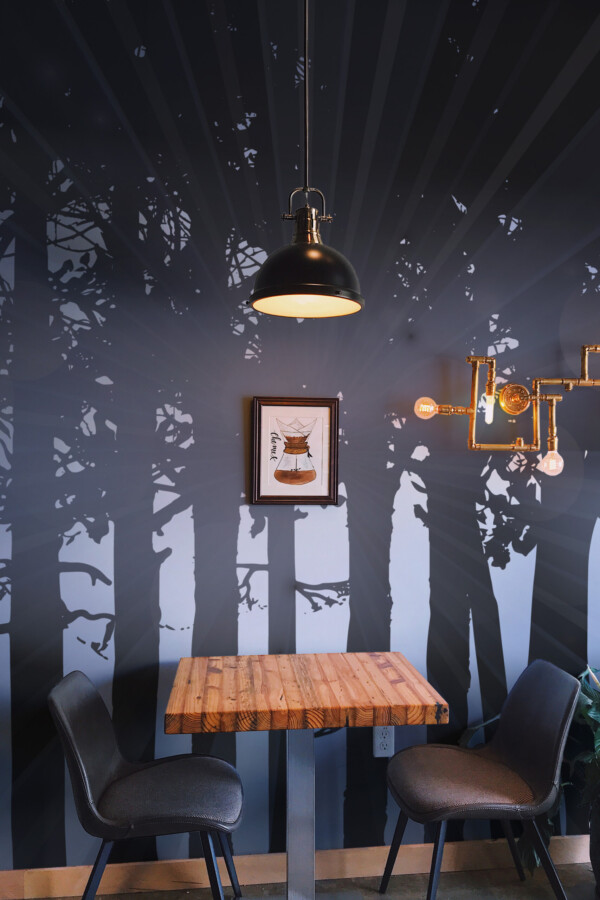 Fancy Walls Dark Woods wall mural peel and stick capturing rays of light shining between tall black trees in a moody atmosphere