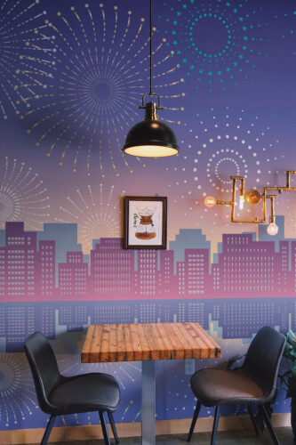 Fancy Walls Festive Cityscape peel and stick wall mural with purple skyline and fireworks.