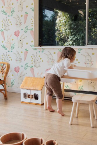 Fancy Walls self-adhesive wallpaper with pastel watercolor bunnies and greenery to create a calming woodland-inspired baby room.