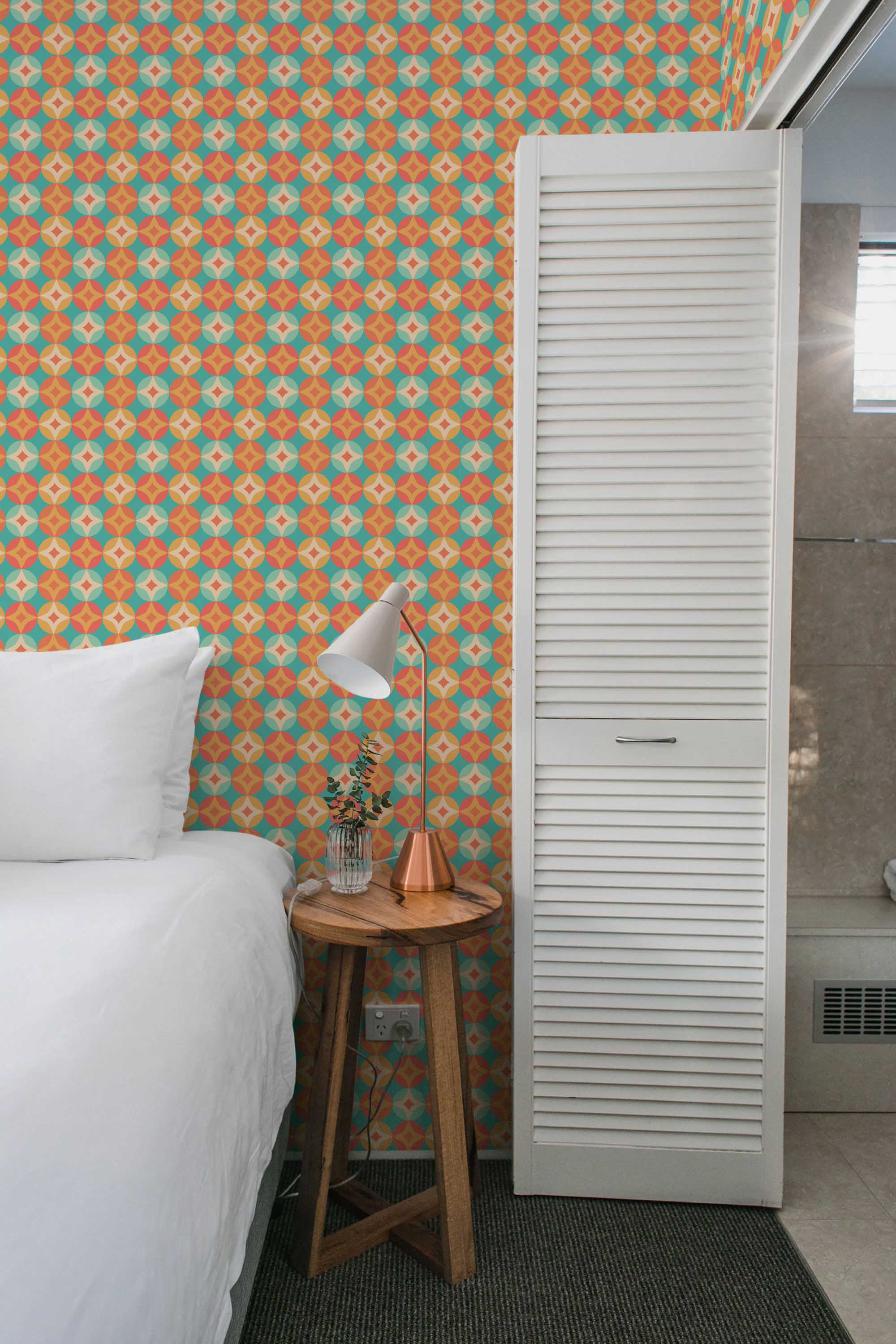 Fancy Walls peel and stick wallpaper featuring warm orange retro starbursts in a playful mid-century pattern.