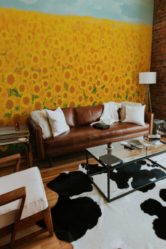 Fancy Walls peel and stick PVC-free wall mural with bright painted sunflower meadow for modern living rooms and warm contemporary interiors.