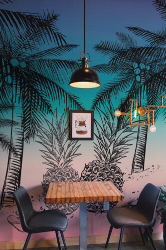 Fancy Walls peel and stick PVC-free wall mural with tropical palm and pineapple sketch design on gradient sunset background for modern living rooms and coastal interiors.