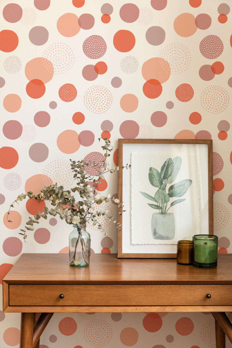 Bold Orange Polka Dot peel and stick wallpaper with overlapping orange and mauve circles behind a console table.