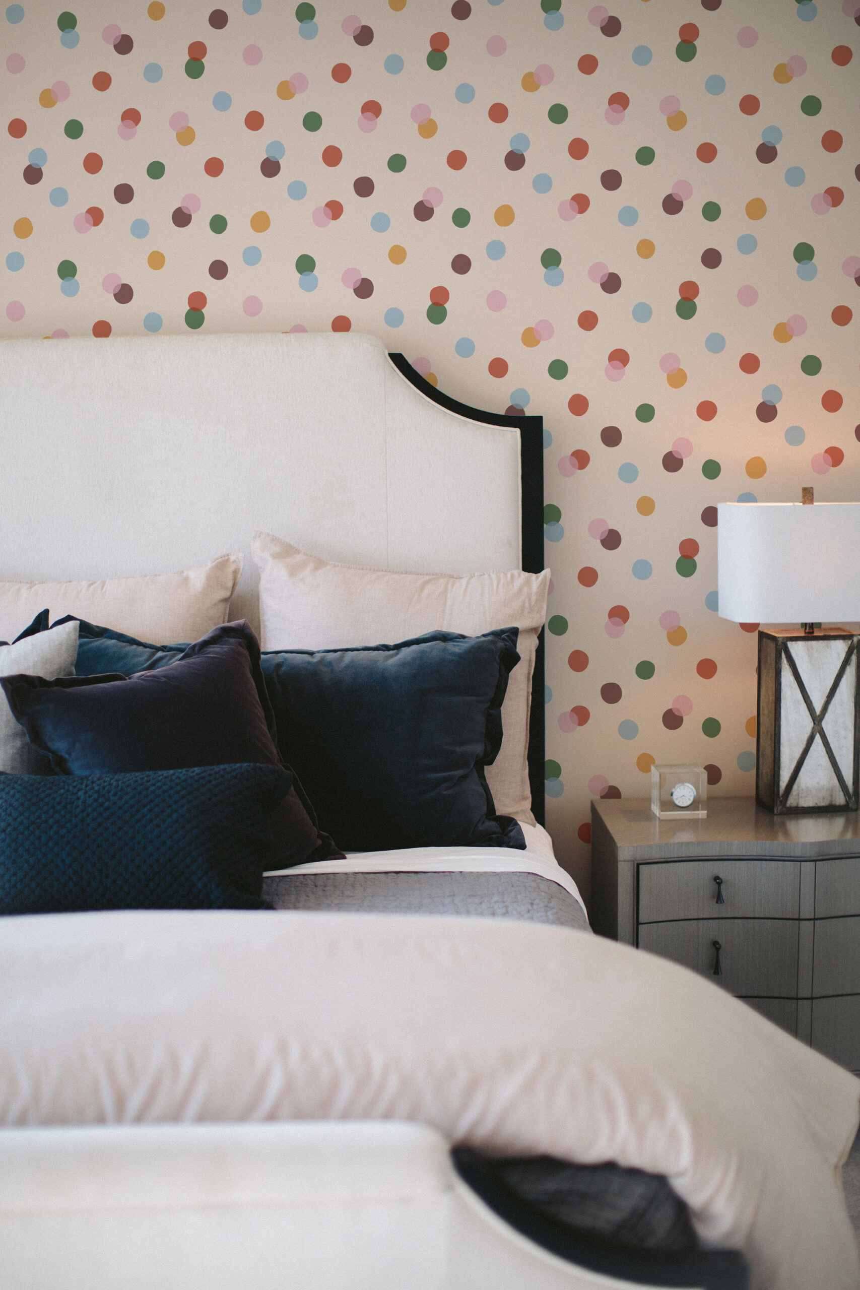 Vintage Colorful Polka Dot pre-pasted wallpaper on a bedroom wall behind an upholstered headboard and nightstand.