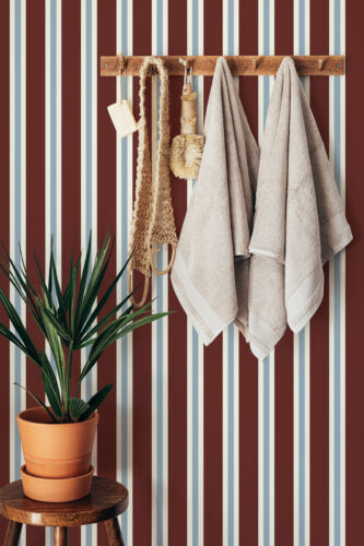 Bold Maroon Striped peel and stick wallpaper with vertical maroon, cream, and pale blue lines behind a wooden towel rack.