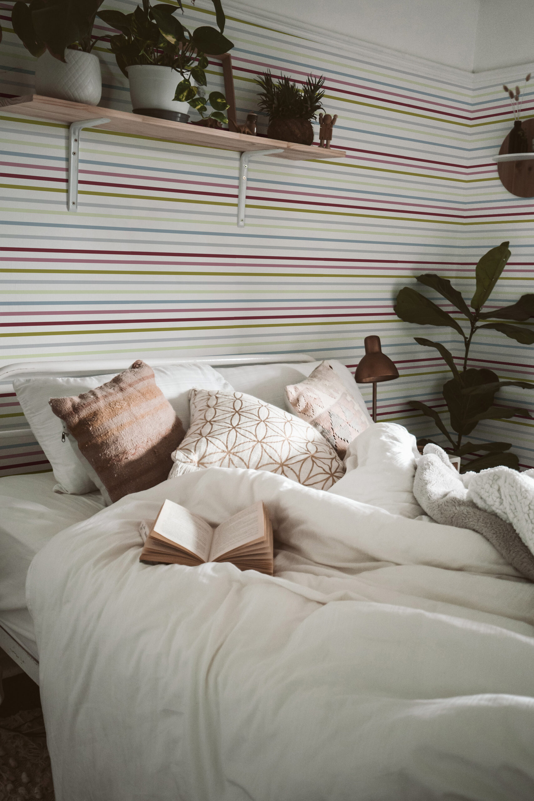 Fine Colorful Stripe adds thin, pastel horizontal lines behind the bed as pre-pasted wallpaper in a cozy bedroom.