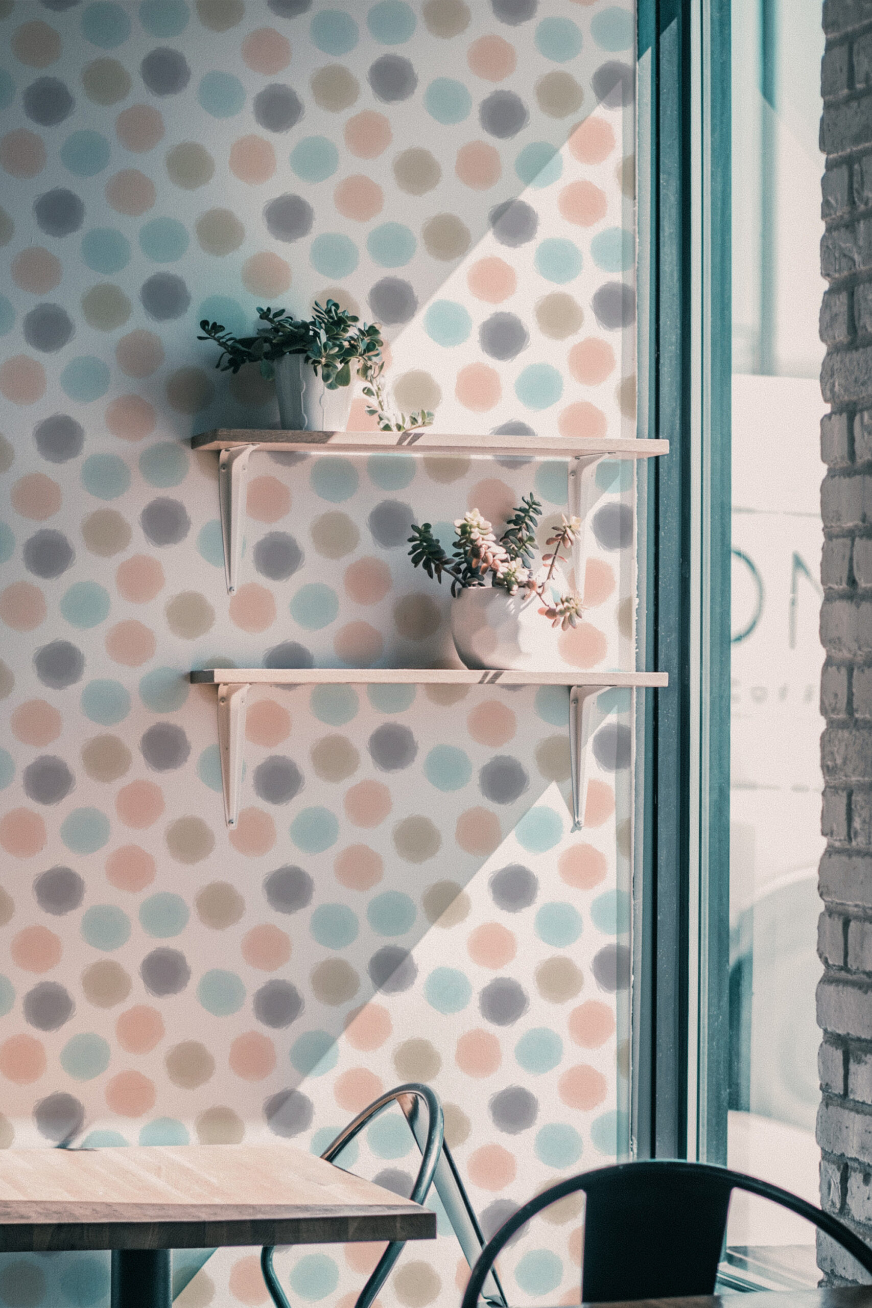 Spaced Beige Dots self-adhesive wallpaper with pastel polka dots behind wall shelves in a bright corner.