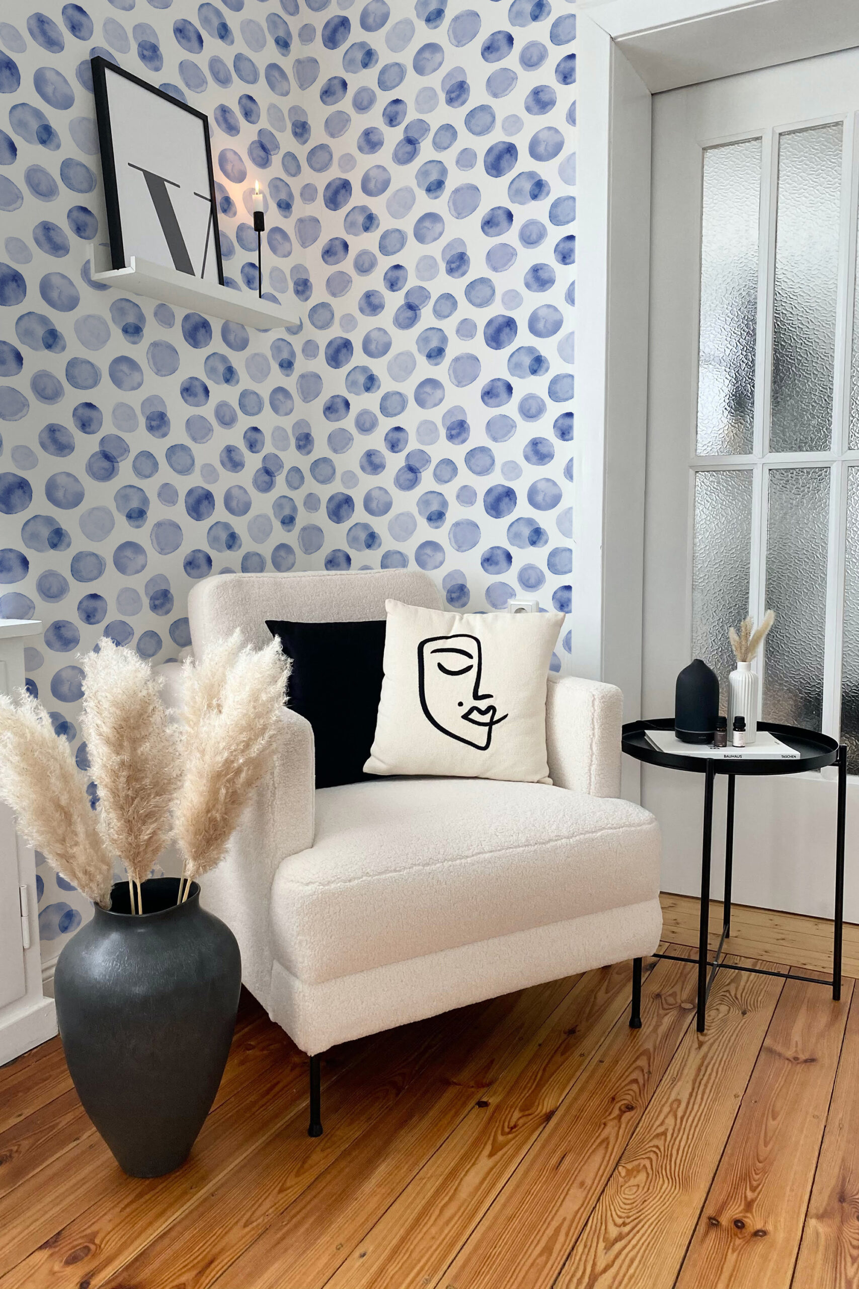 Soft Blue Dots self-adhesive wallpaper with watercolor-style blue circles covering an accent wall behind a chair.