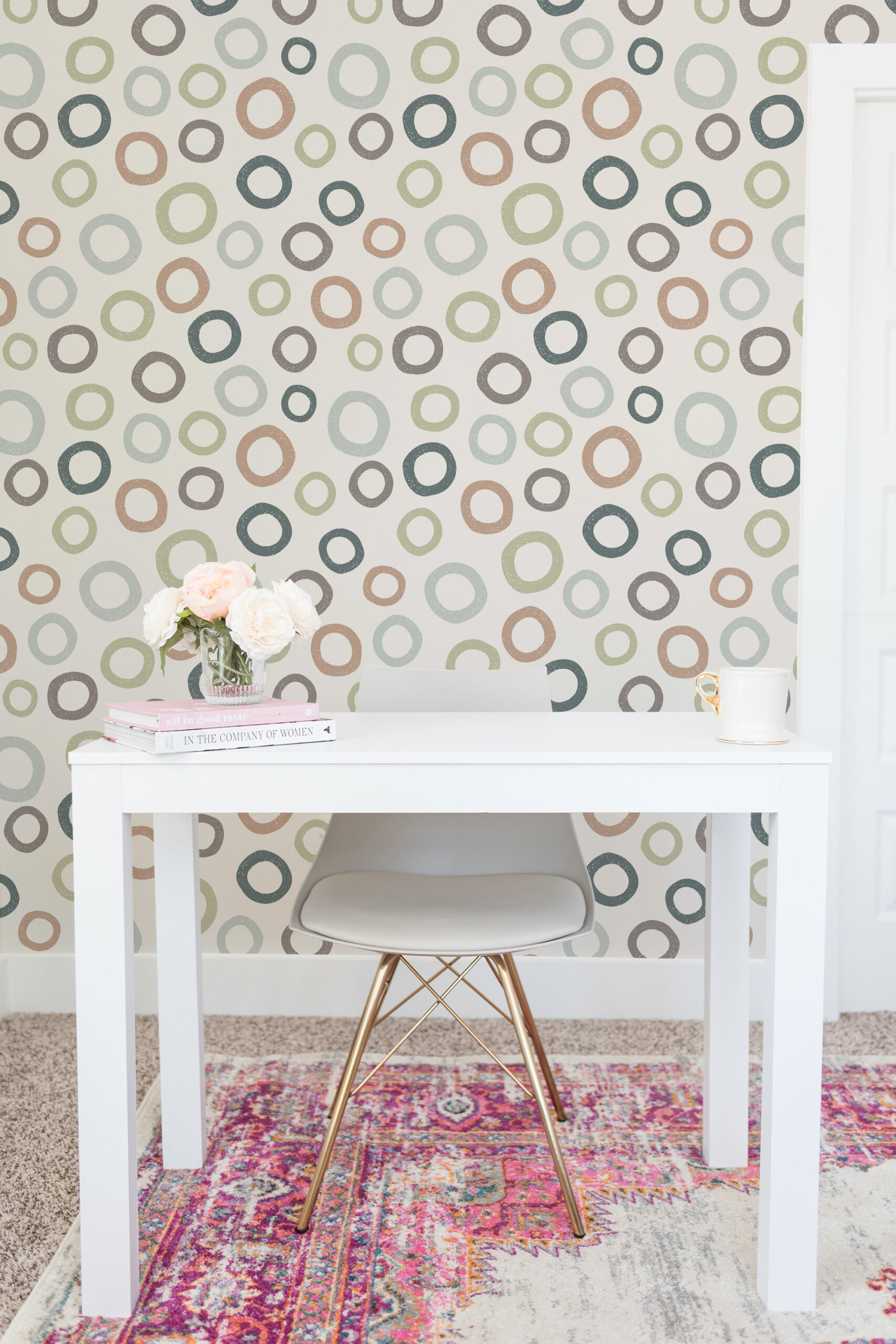 Scattered Beige Ring Dots pre-pasted wallpaper with multicolor ring dots on a wall behind a white desk and chair.